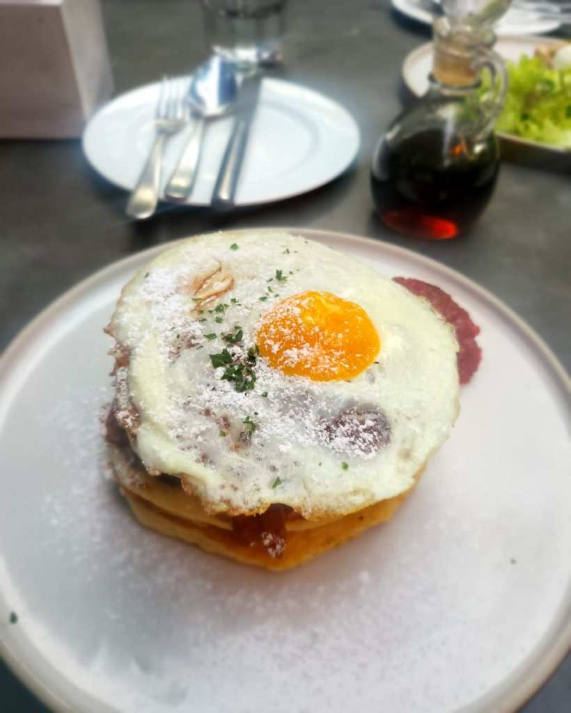 Showcases pancakes a plate with pancakes, bacon and a fried egg