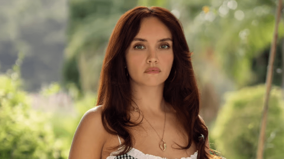 A headshot of actress Olivia Cooke, with long brown hair and a serious expression, portraying Cherry Laine in "The Girlfriend" series.